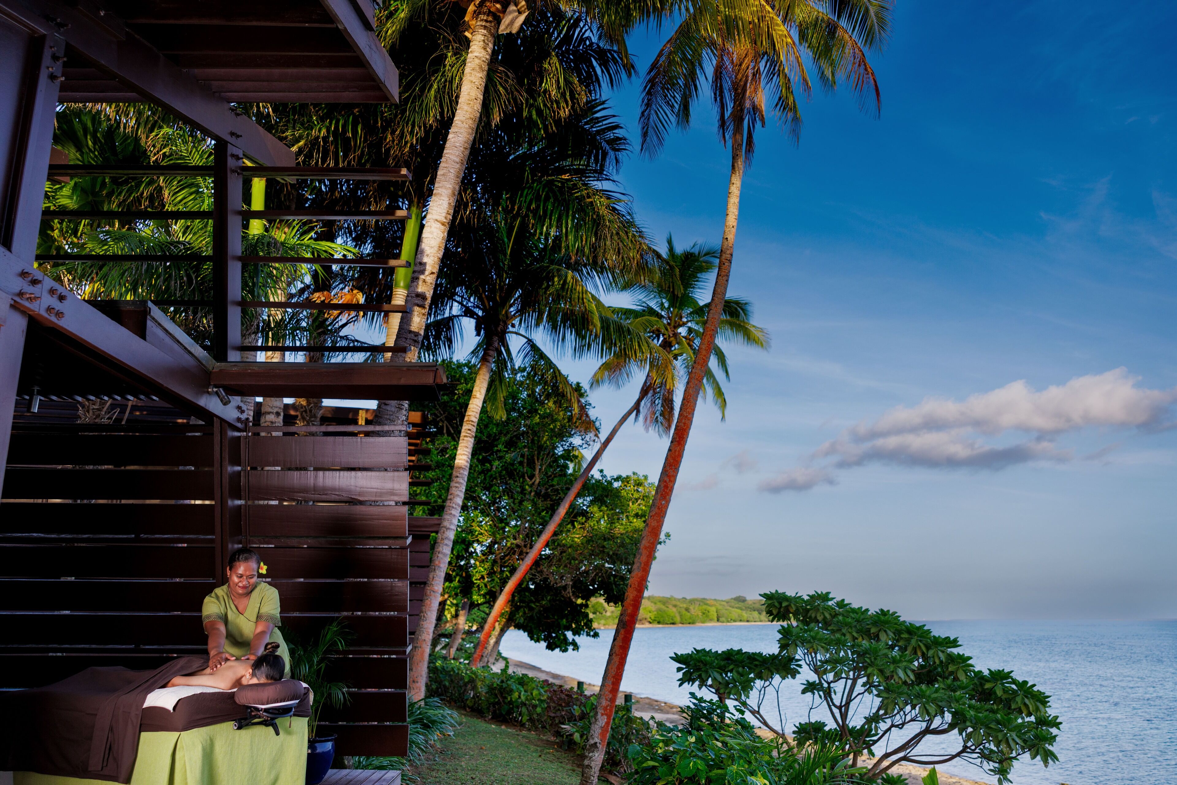 A massage parlor with a view of the ocean and palm trees.