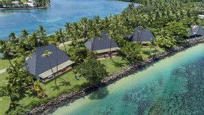 An aerial view of a resort with multiple buildings, a stone-lined beach, and a clear blue sea. - Shangri-La Yanuca Island, Fiji (Yanuca Island)