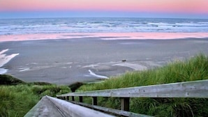 A beach with a wooden walkway leading to the water, a clear sky, and a visible moon. - Seagrass Oceanfront Inn (Newport)