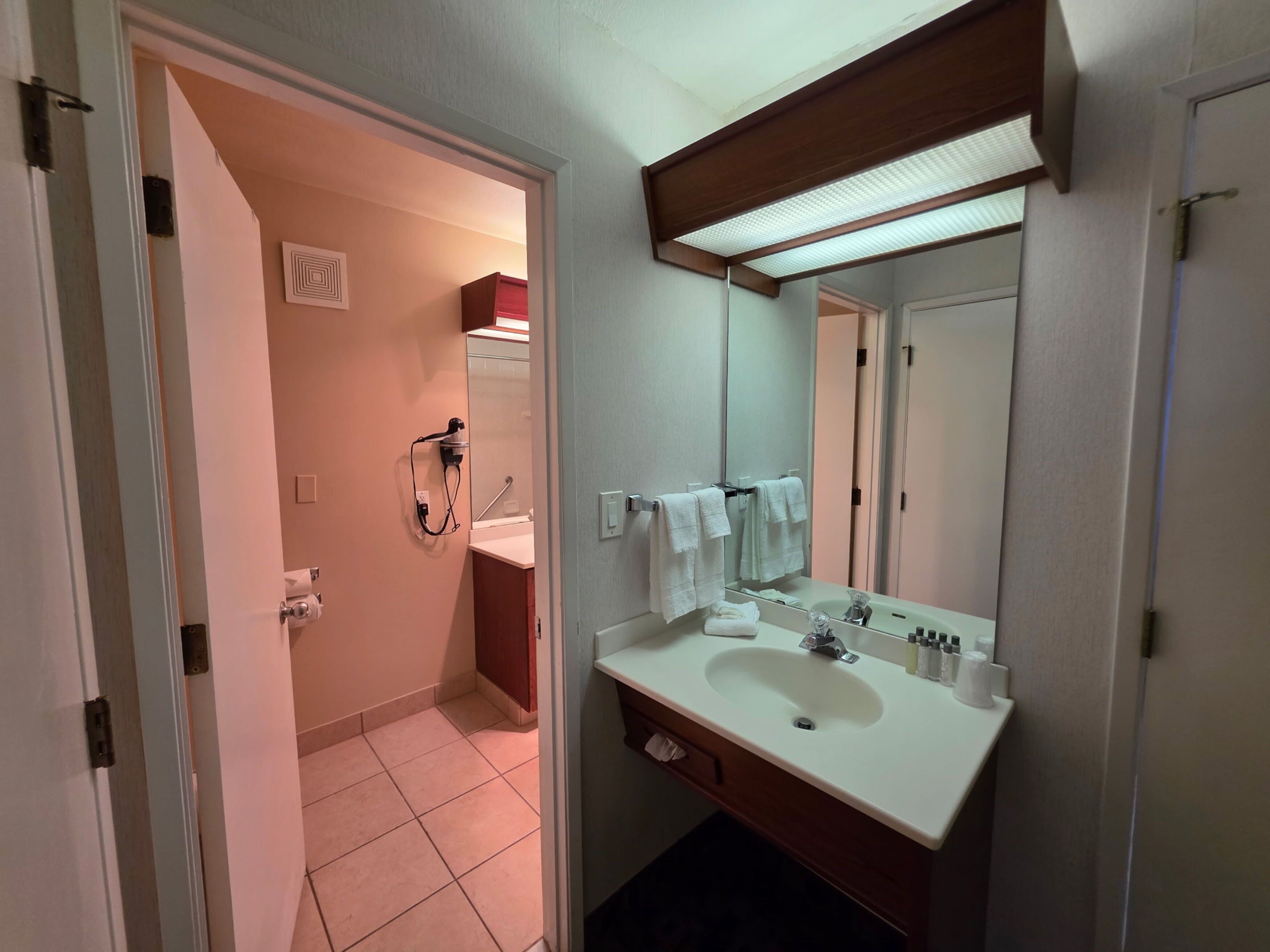 A bathroom with a white sink, mirror, and towel rack.