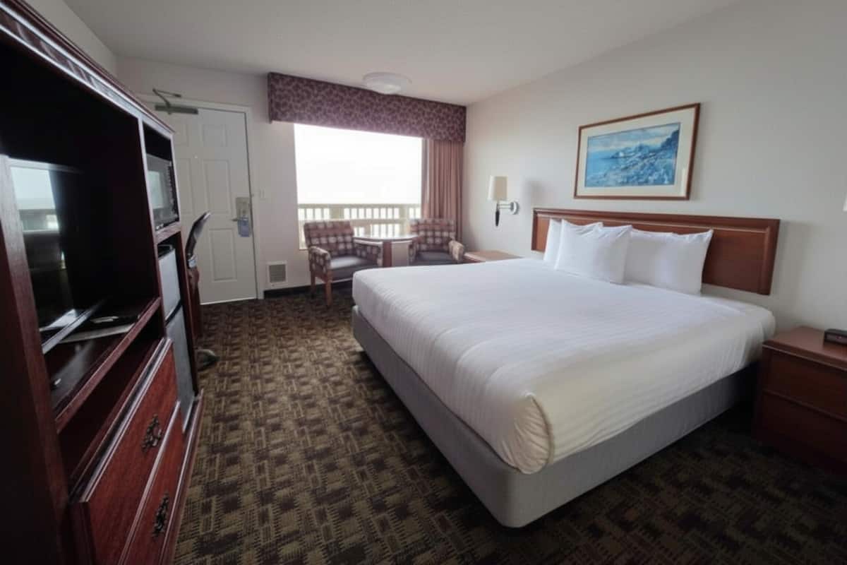 A hotel room with a large bed, a television, a desk, and a chair.