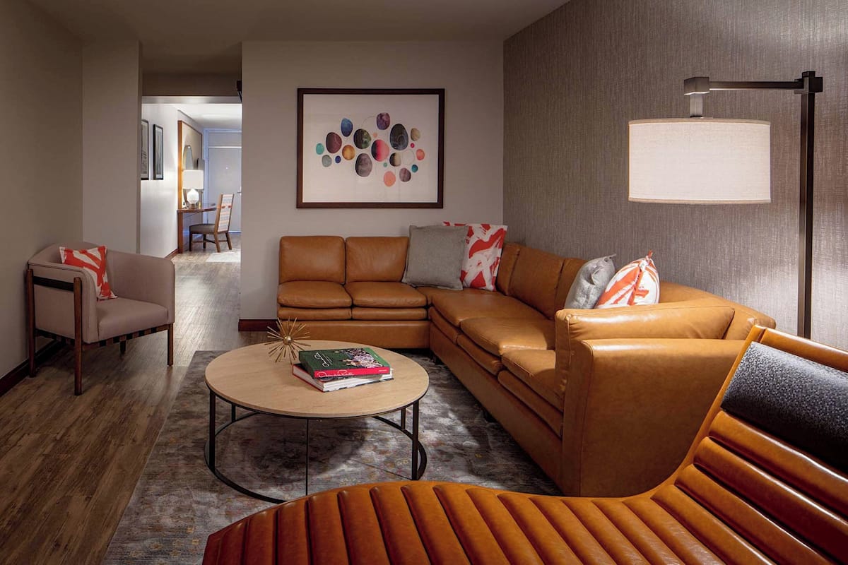 Ein modernes Wohnzimmer mit einer braunen Ledersofa, einem runden Couchtisch und einem gemusterten Teppich.