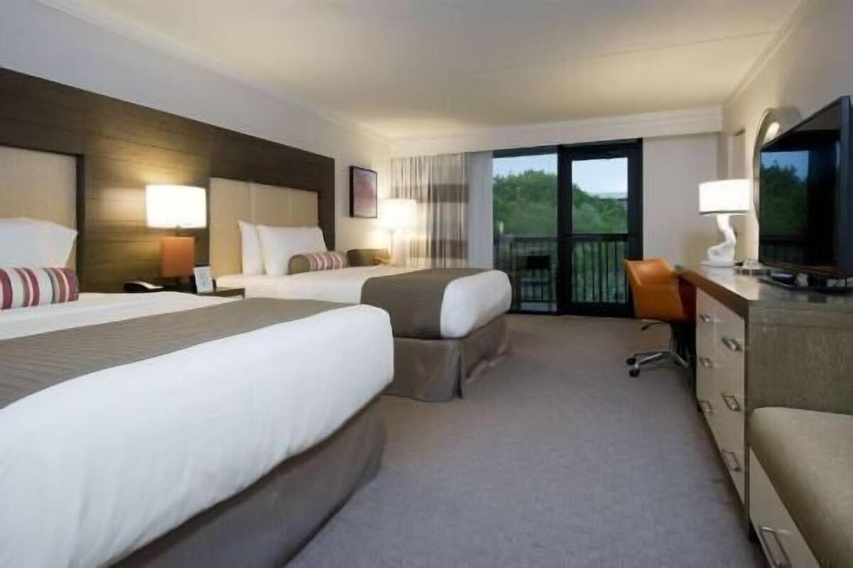 Ein Hotelzimmer mit zwei Betten, einem Schreibtisch mit Fernseher und einem Balkon mit Blick.