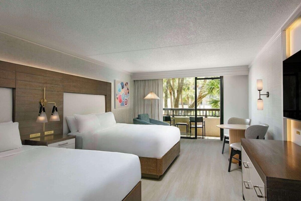 Ein Hotelzimmer mit zwei Betten, einem Essbereich und einem Balkon mit Blick.