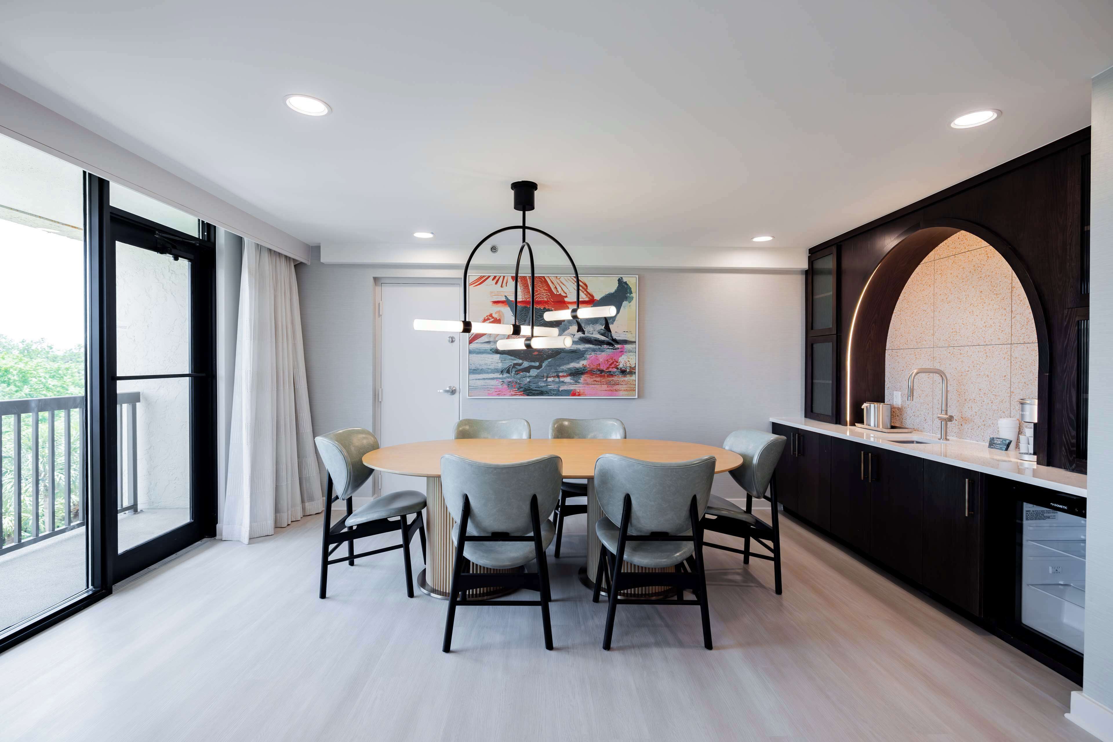 A modern dining area with a round table, six chairs, and a large window.