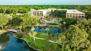 Een luchtendakfoto van een resort met een centraal zwembad, meerdere gebouwen en weelderige begroeiing.