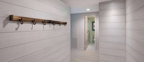 A hallway with light wood paneling and a coat rack.