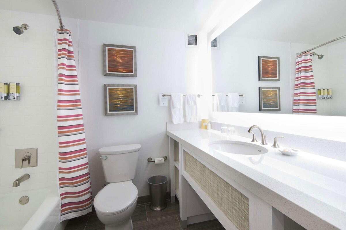 Un baño moderno con inodoro, bidé, lavabo y cortina de ducha.