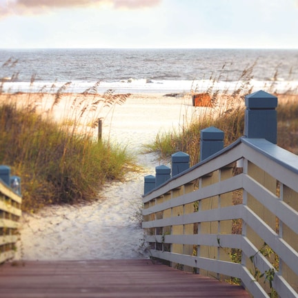 A wooden boardwalk leading to a beach with a view of the ocean.