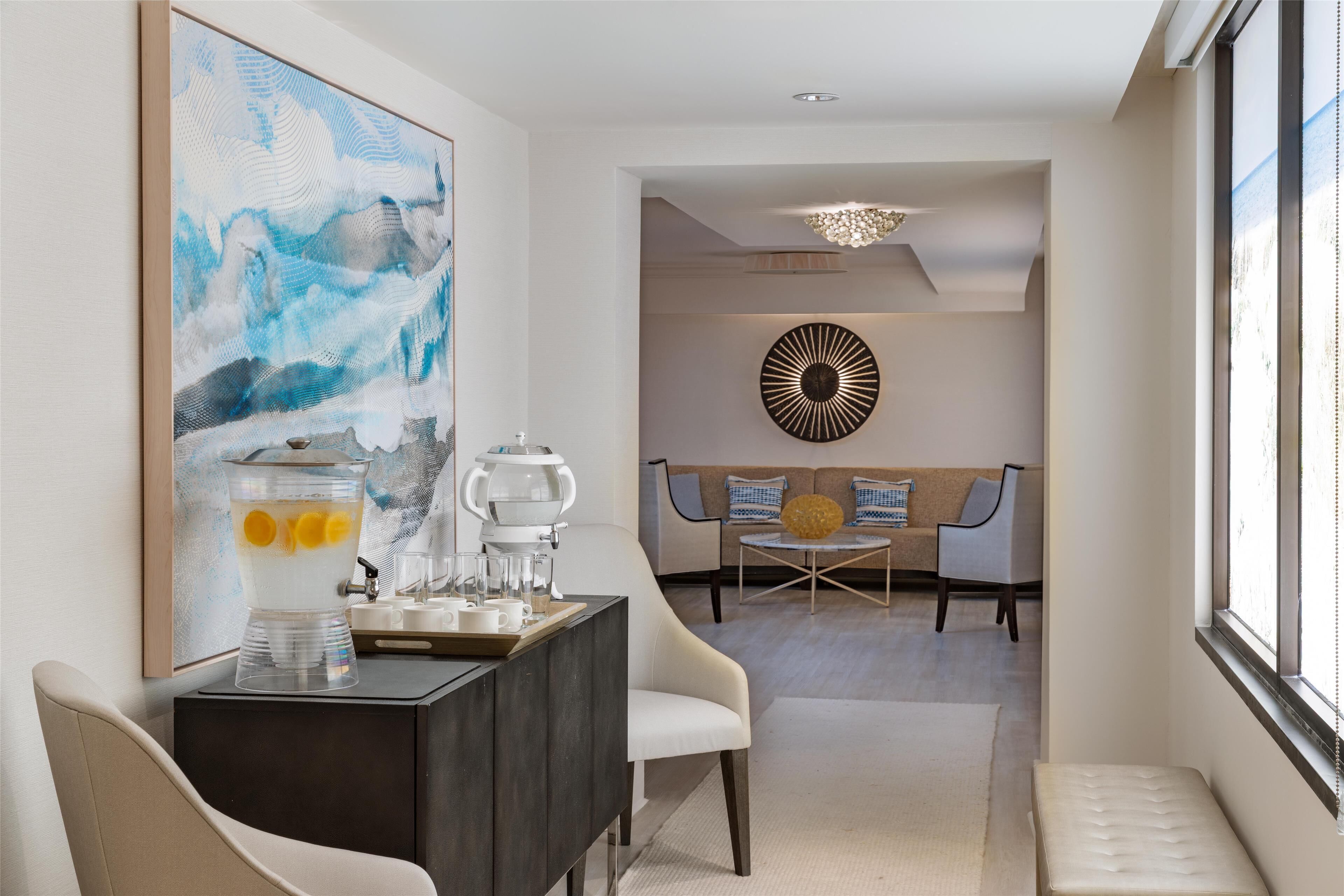 A modern living room with a coffee station, a large abstract painting, and a round wall decoration.