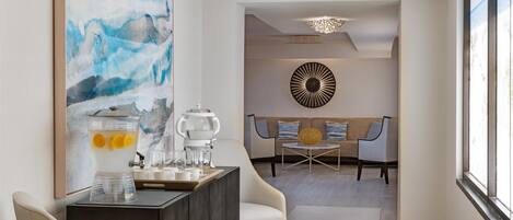 A modern living room with a coffee station, a large abstract painting, and a round wall decoration.