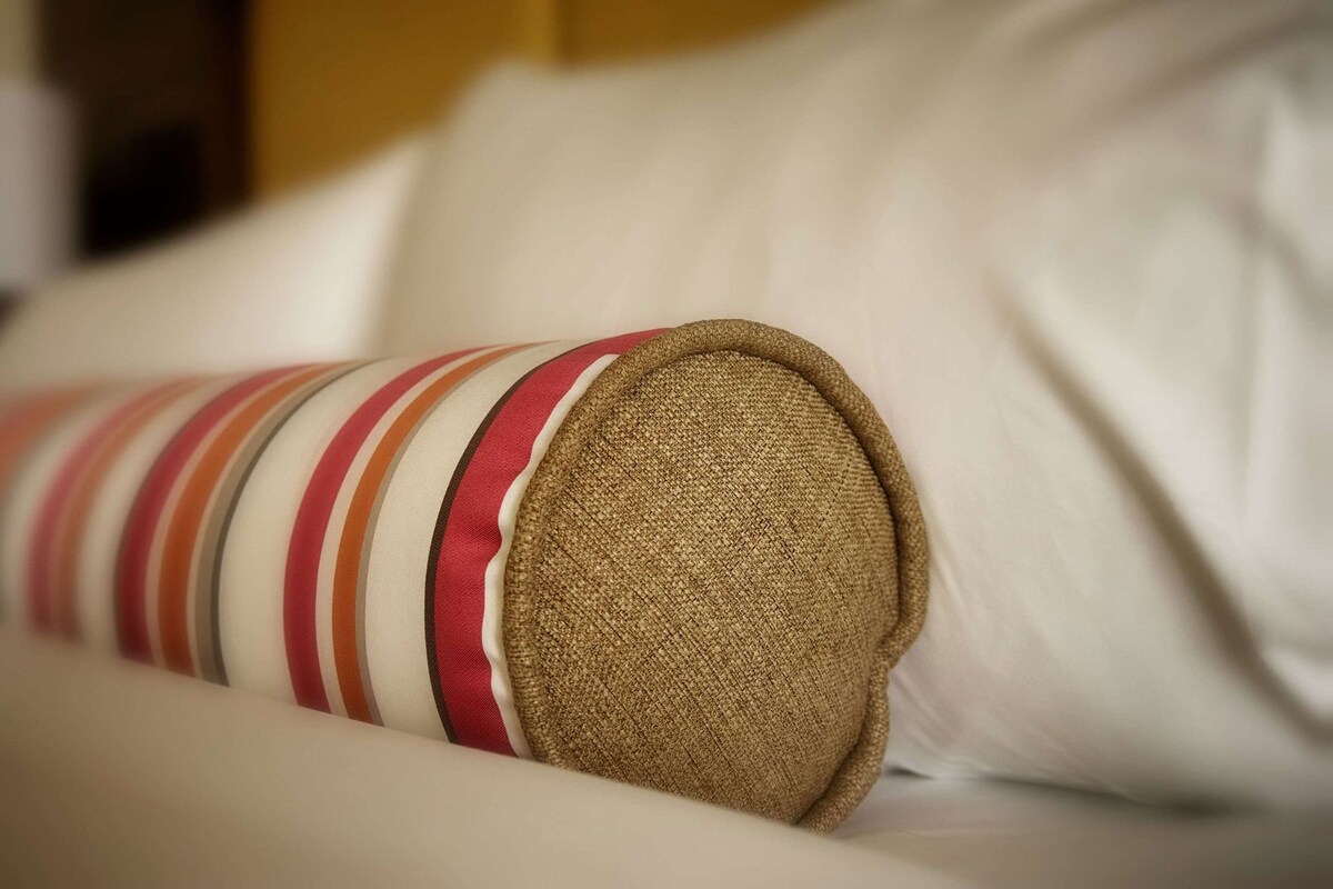A close-up of a striped pillow with a textured cover on a bed.