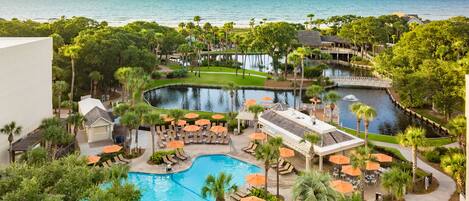 Un resort con una piscina grande, palmeras y vistas al océano.