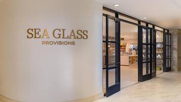 Una tienda llamada 'Sea Glass Provisions' con un muro curvo y puertas de cristal que dan acceso al interior.