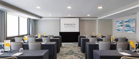 A conference room with tables, chairs, and a projector screen displaying "SONESTA HILTON HEAD ISLAND".
