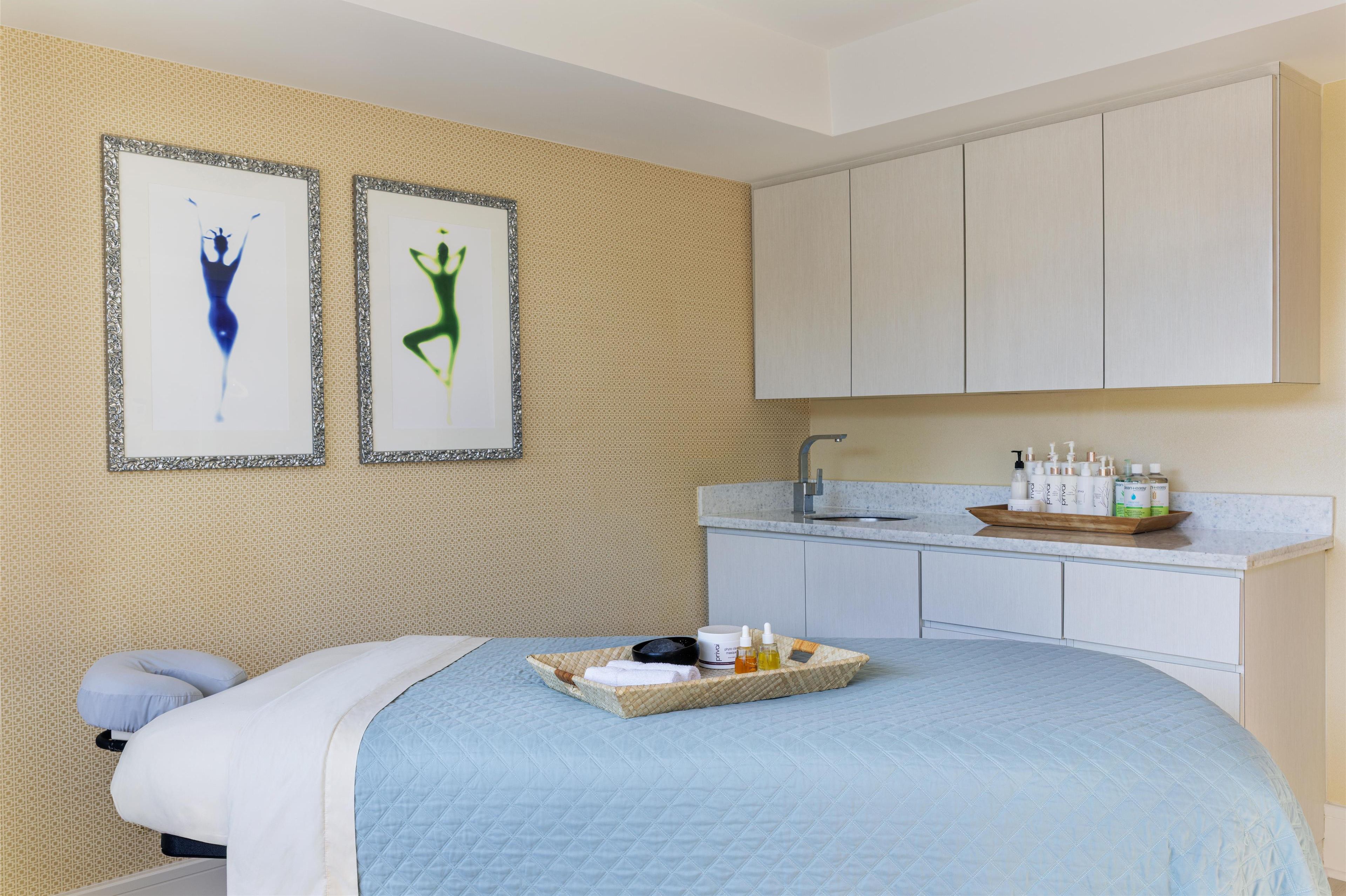 A bedroom with a bed, a small bedside table, a tray with toiletries, and a wall with two framed pictures.