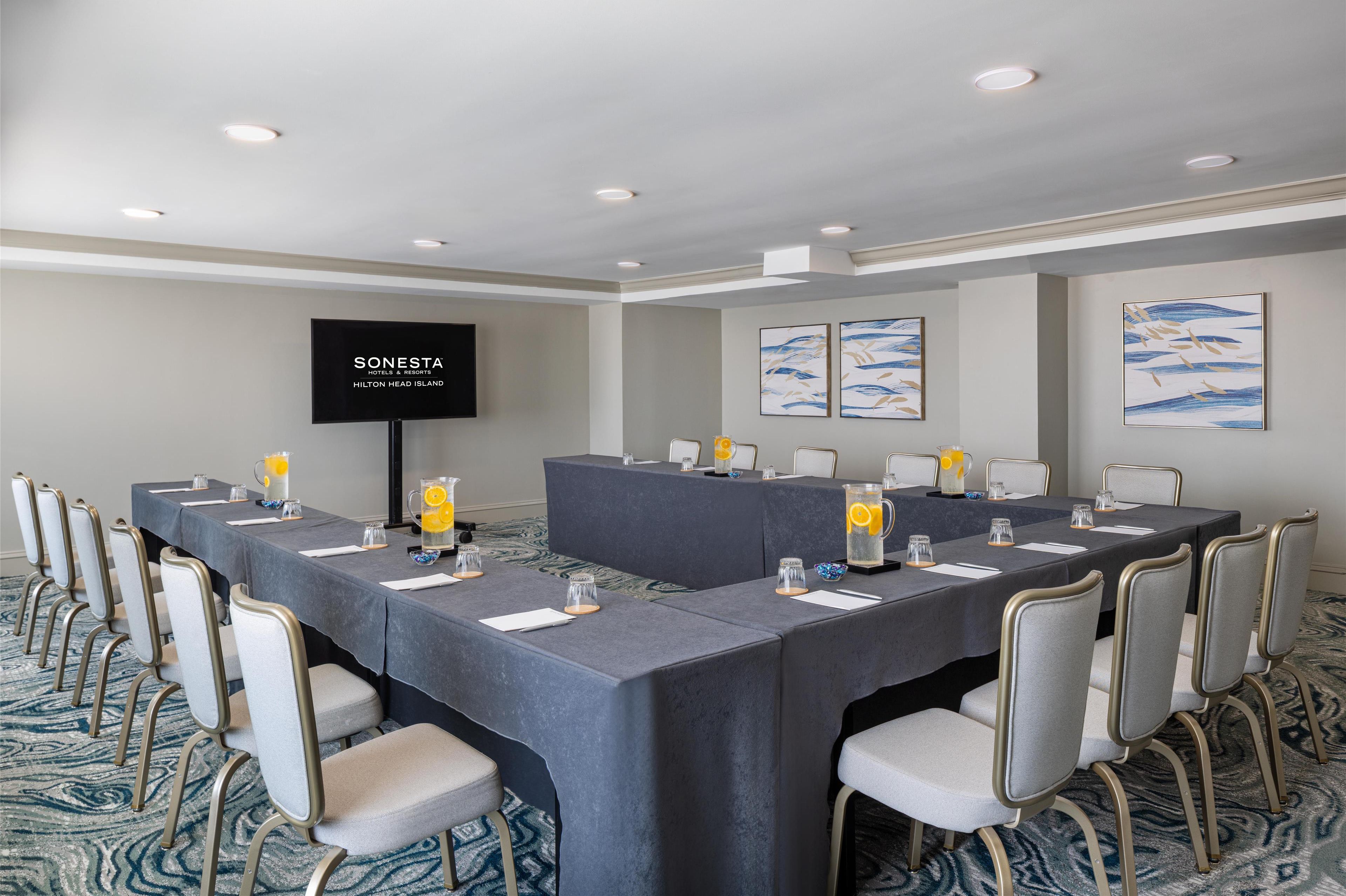 A conference room with a long table, chairs, a TV screen, and artwork on the walls.