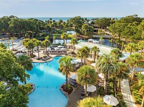 Un resort con una amplia piscina, palmeras y vista al océano.