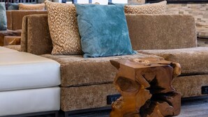 A modern lobby with a stone wall, a wooden coffee table, and a sofa with patterned cushions.