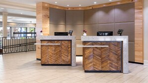A reception area with two wooden reception desks, a modern interior, and a view of the outdoors.