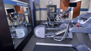 Un gimnasio con diferentes máquinas de ejercicio, un reloj y un letrero motivacional.