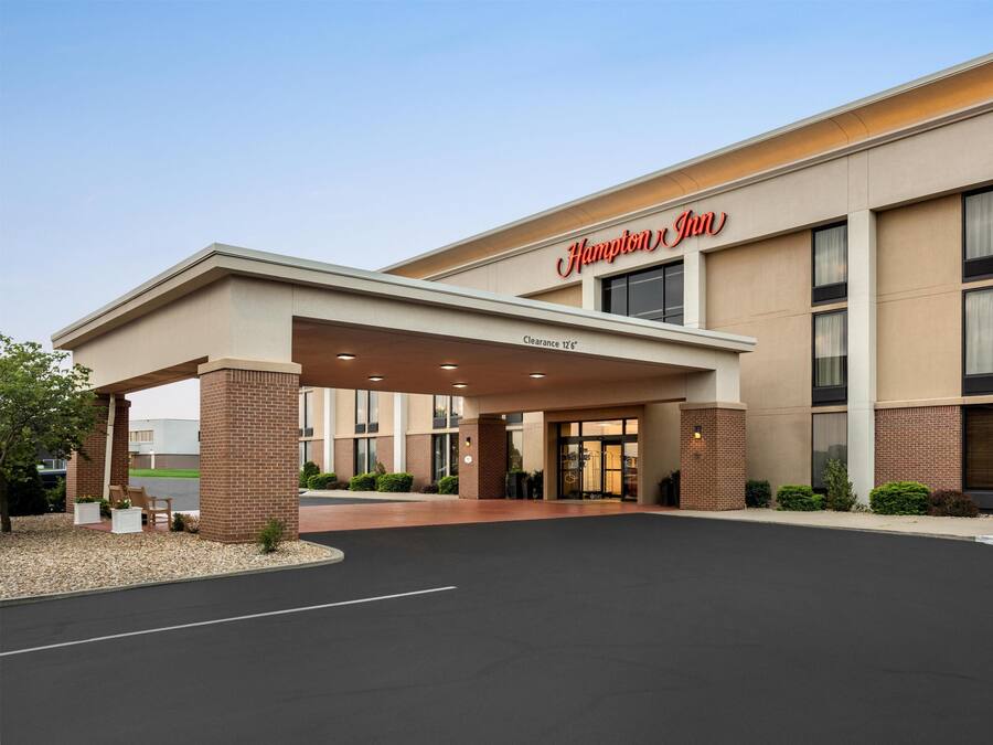 A Hampton Inn hotel entrance with a covered walkway, clear signage, and a parking lot.