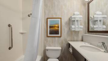 Un baño con ducha, inodoro, lavamanos, toallero y un cuadro en la pared.