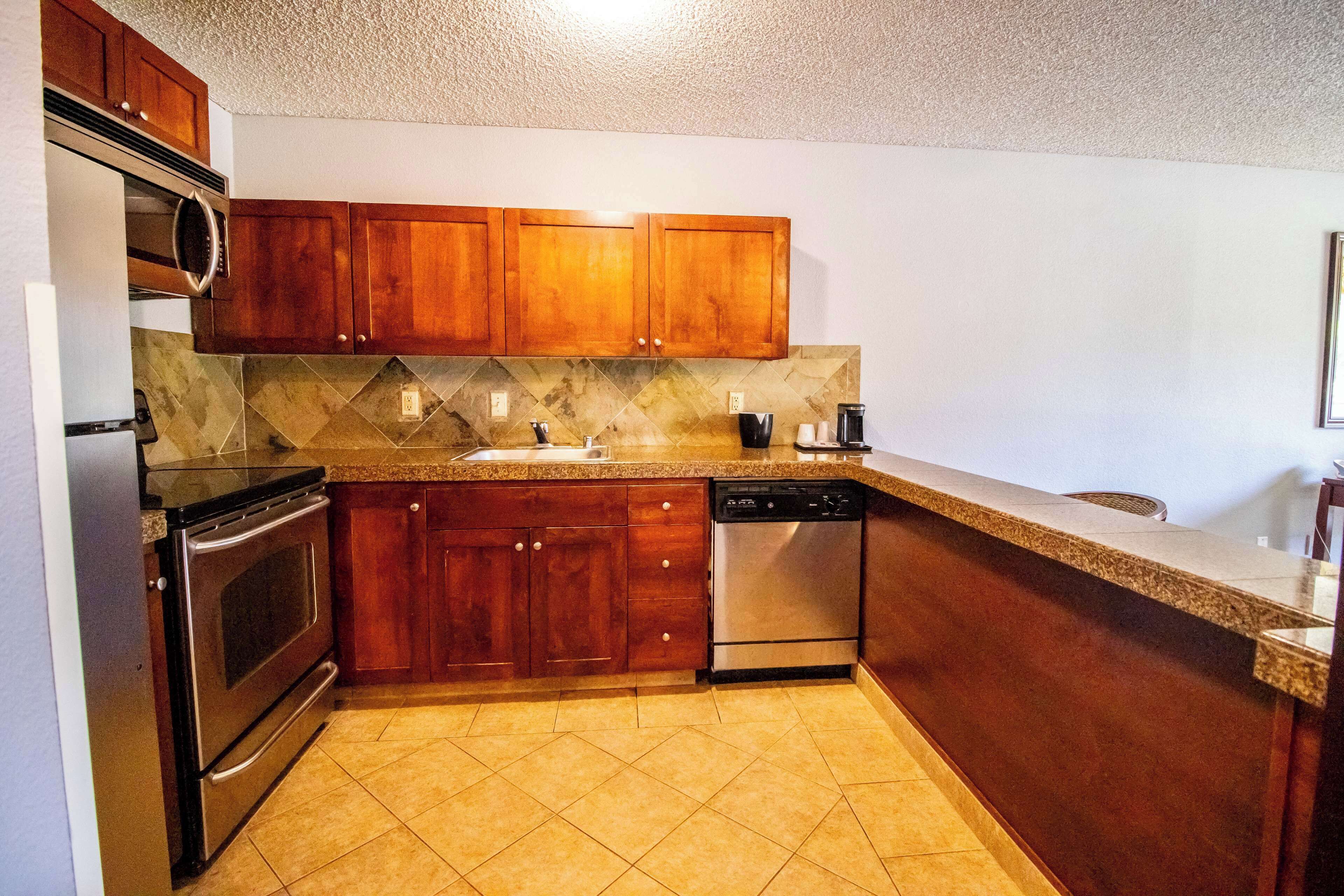 A kitchen with wooden cabinets, a stainless steel dishwasher, and a granite countertop.