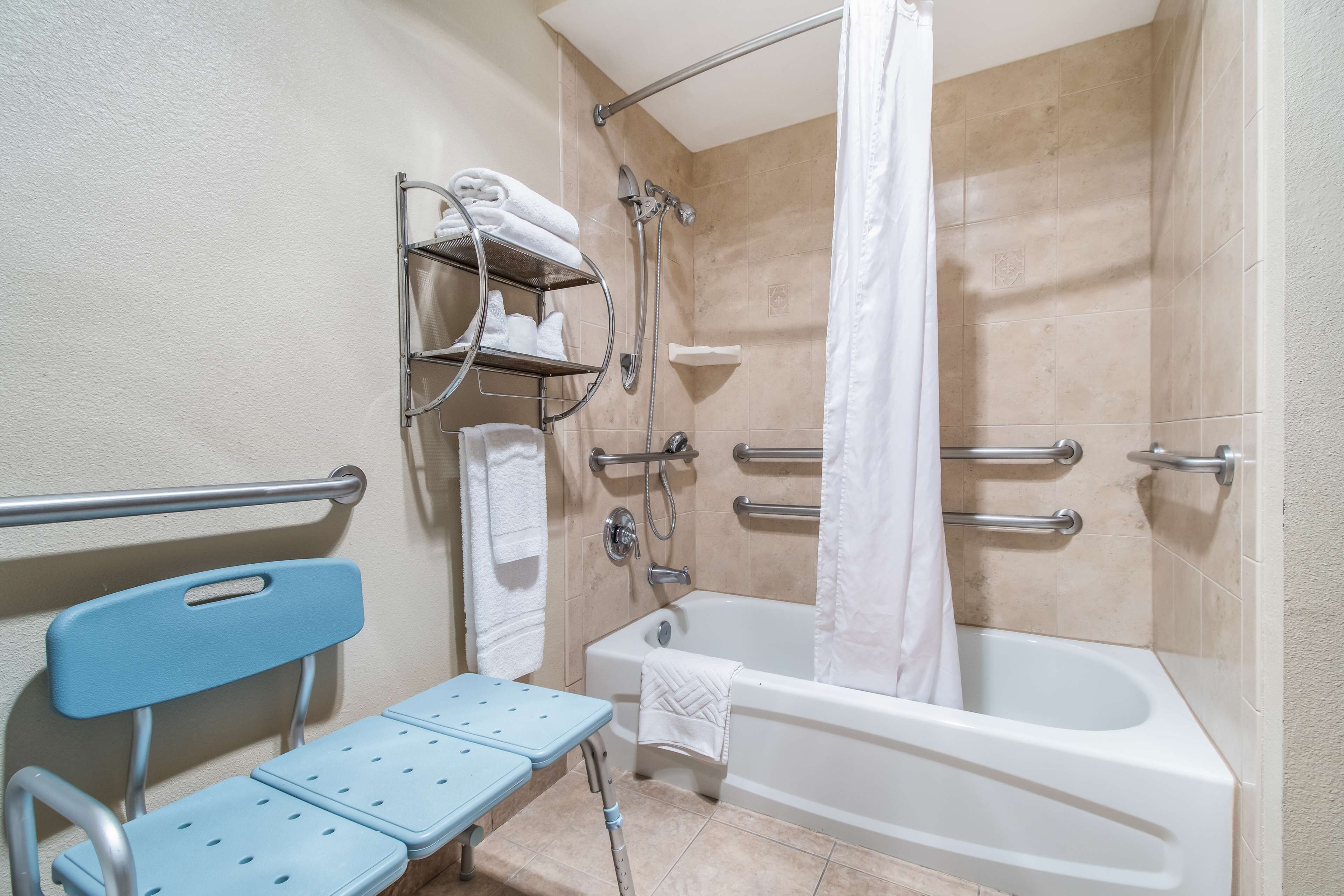A bathroom with a shower, a bathtub, a toilet, and a wheelchair-accessible bench.