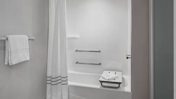 Une salle de bain moderne avec une baignoire, un rideau de douche et un porte-serviettes.