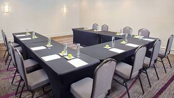 Un salón de conferencias con una mesa larga, sillas y botellas de agua.