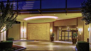 Entrada de hotel con pared de ladrillo, una planta grande en maceta y un área de acceso bien iluminada.