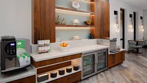 Una cocina moderna con cafetera, frutero y refrigerador.
