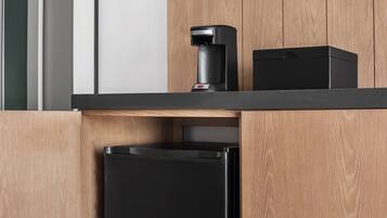 Eine Küche mit einer Kaffeemaschine, einer schwarzen Box und einem schwarzen Kühlschrank.
