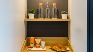A compact kitchen with a microwave, shelf with bottles, and a small potted plant. - ibis Styles Paris Place d'Italie Butte aux Cailles Hotel (Paris)