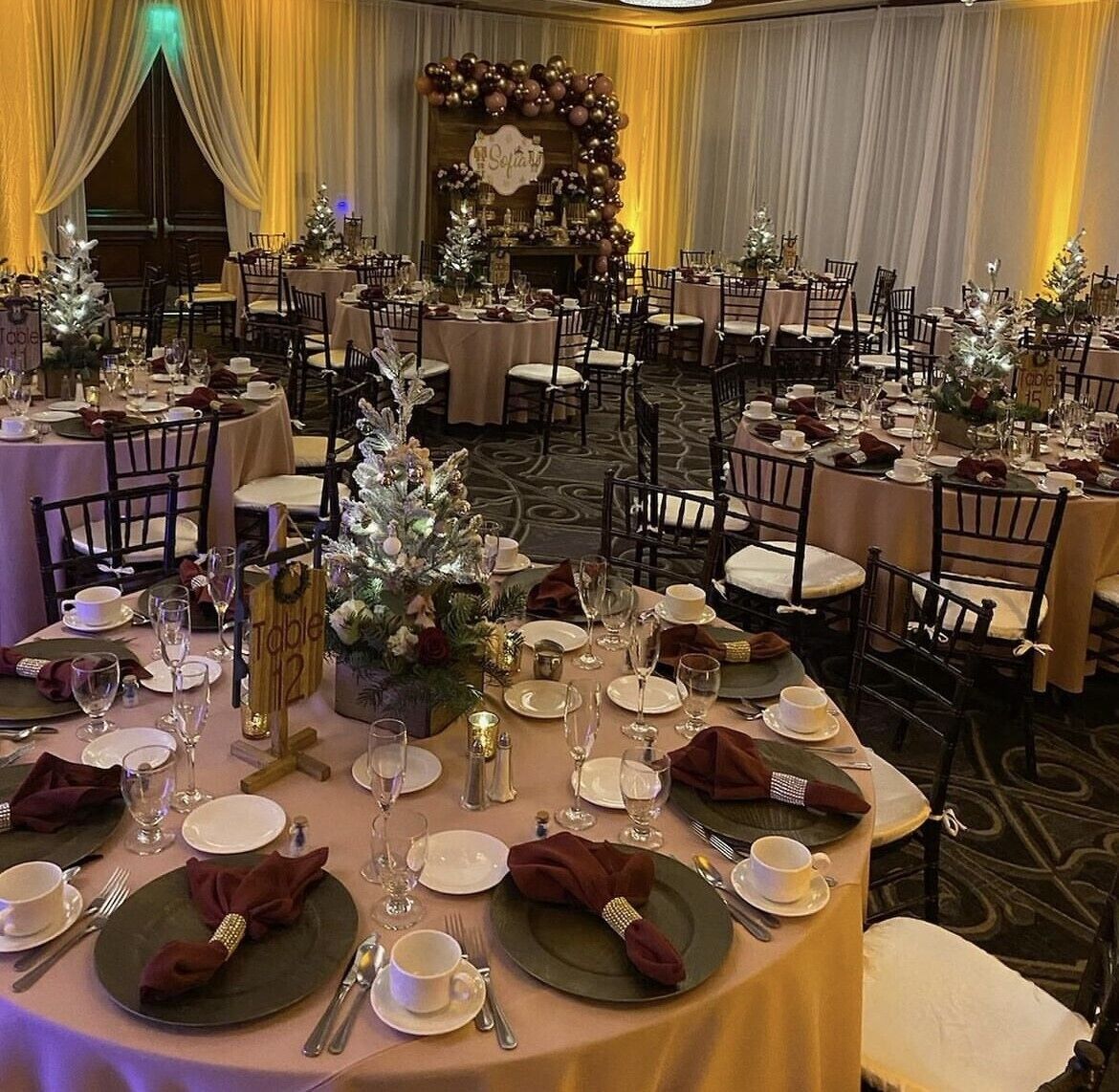 A banquet hall with round tables set for a formal event, complete with place settings and floral centerpieces.