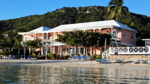 A beachfront property with a large building, multiple balconies, and a dock with boats. - Catamaran Hotel Marina (Falmouth Harbour)
