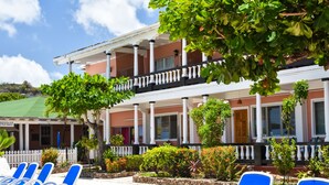 A hotel with a balcony, lounge chairs, and a garden area. - Catamaran Hotel Marina (Falmouth Harbour)