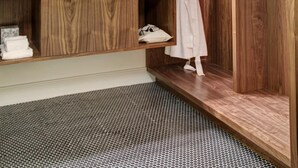 A modern bathroom with a wooden vanity, a large mirror, and a robe hanging on a rack. - Hotel Durant (Aspen)
