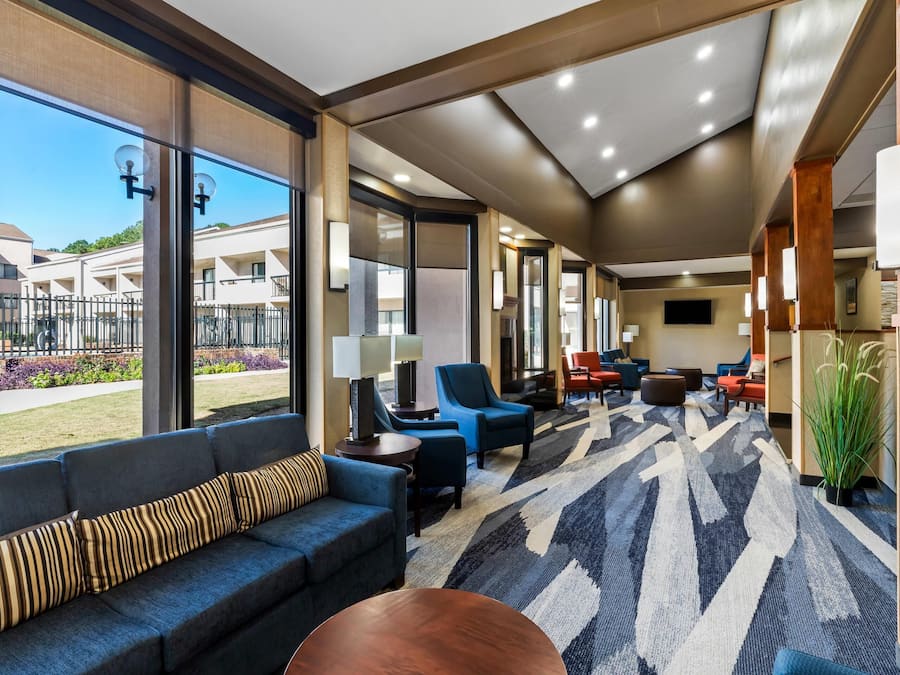 Een moderne hotellobby met een ruim zitgedeelte, een kamerbreed tapijt en grote ramen met uitzicht op het buitengebied.