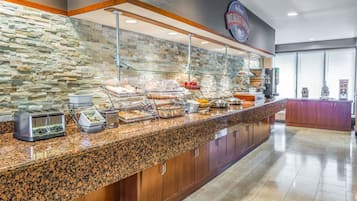 A breakfast buffet with various food items, a stone wall, and a sign that reads "Breakfast Corner".