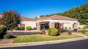A modern building with a covered entrance, stone pillars, and well-maintained landscaping.
