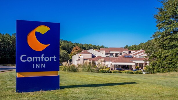 A Comfort Inn sign with a crescent moon logo, surrounded by a well-maintained lawn and a building with a red roof.