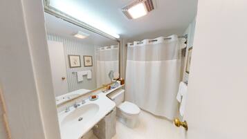 A bathroom with a sink, toilet, and shower curtain.
