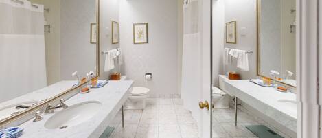 A modern bathroom with two sinks, a toilet, and a shower.