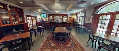 Un restaurante con zona de bar, varias mesas y sillas.