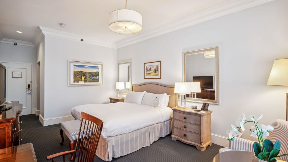 A hotel room with a large bed, bedside tables, a desk, and a chair.