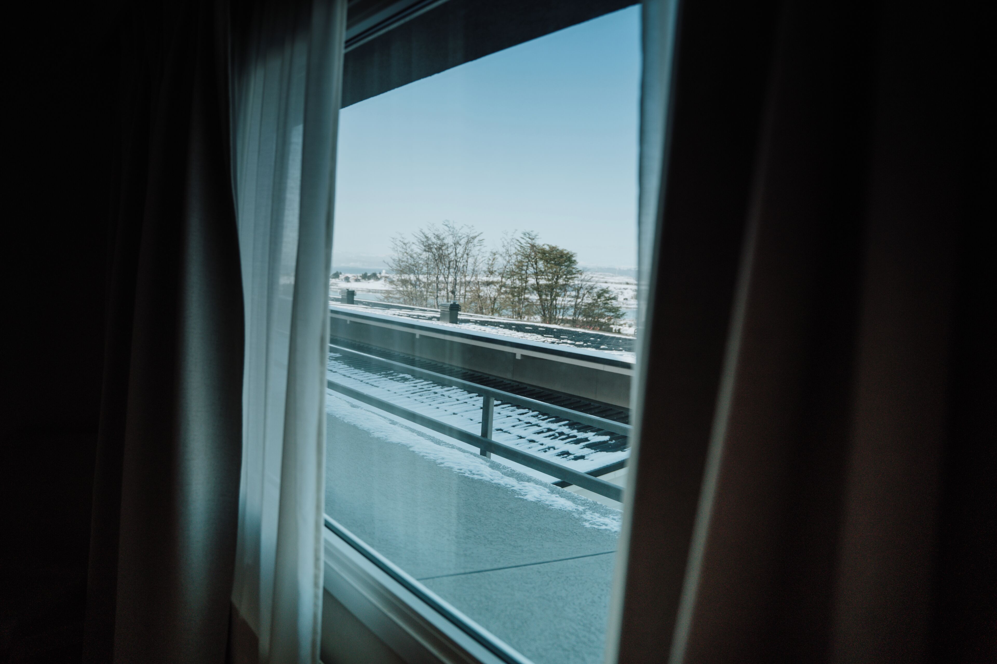 A window with a view of a snowy landscape and a bridge.