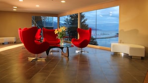A modern interior with a large window, red chairs, a glass table, and a white sofa. - Las Lengas Hotel (Ushuaia)