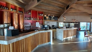 A modern bar area with wooden accents, copper brewing equipment, and a variety of bottles on shelves. - Las Lengas Hotel (Ushuaia)